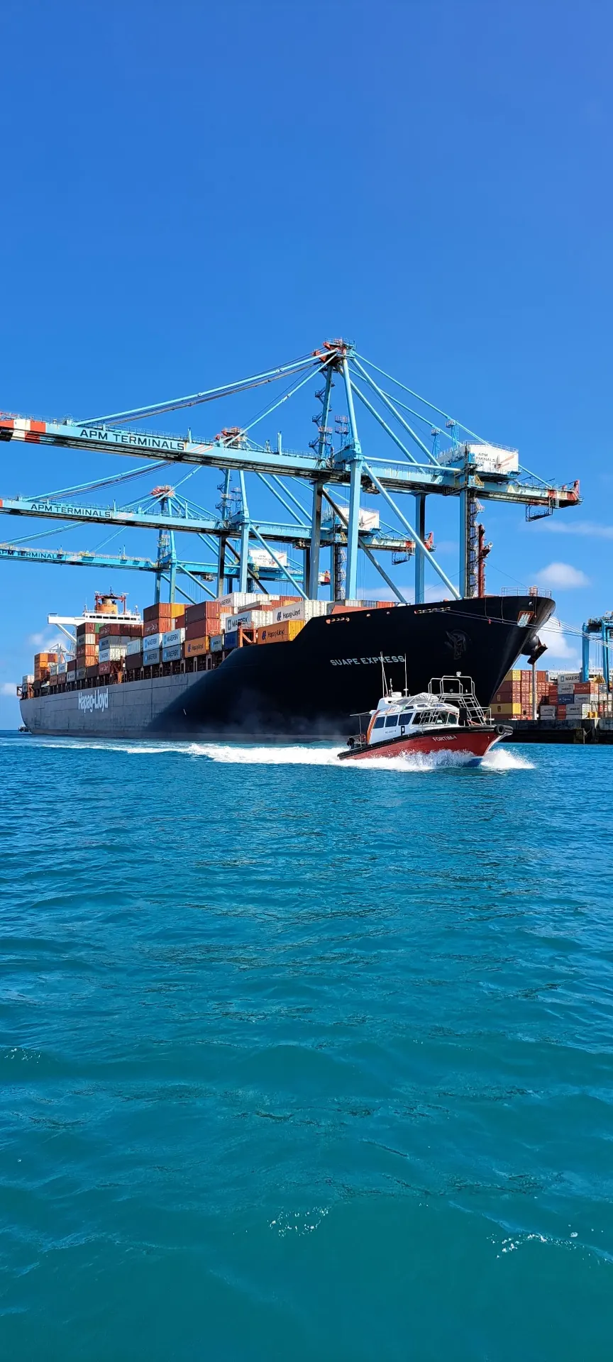 Lancha Fortim ao lado de navio porta-contêineres em operação portuária