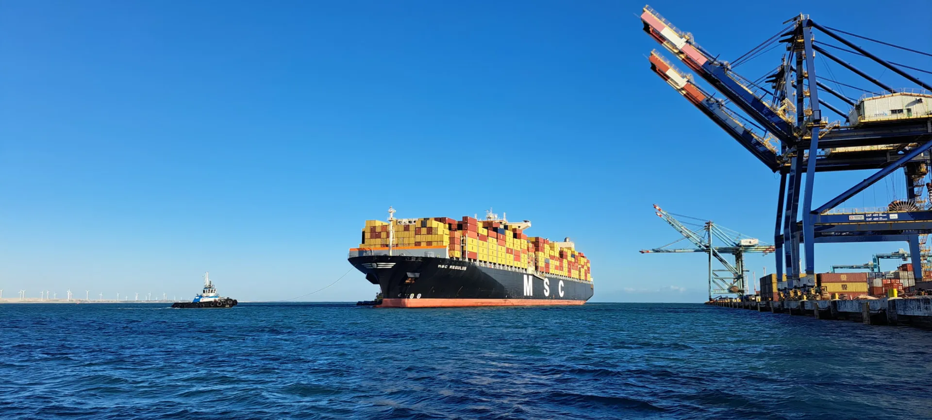 Navio porta-contêineres MSC Regulus em manobra de atracação com apoio de rebocador no Terminal do Pecém